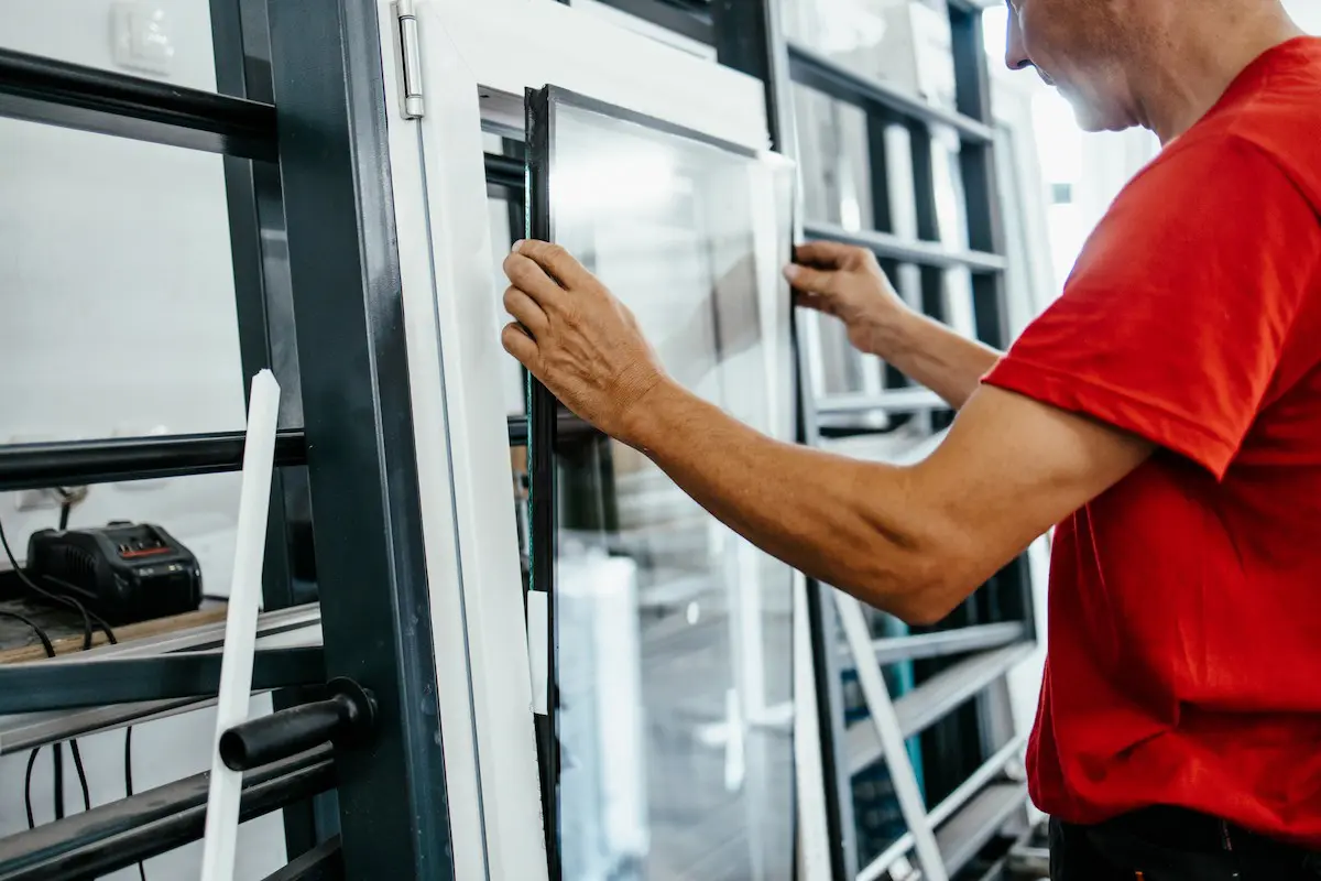 Employé de menuiserie en train de poser un vitrage sur une fenêtre pvc blanche