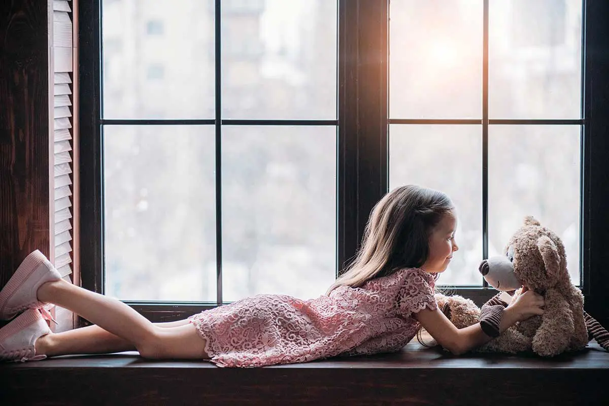 Petite fille installée devant une fenêtre