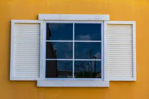 Fenêtre blanche avec croisillons sur un mur jaune